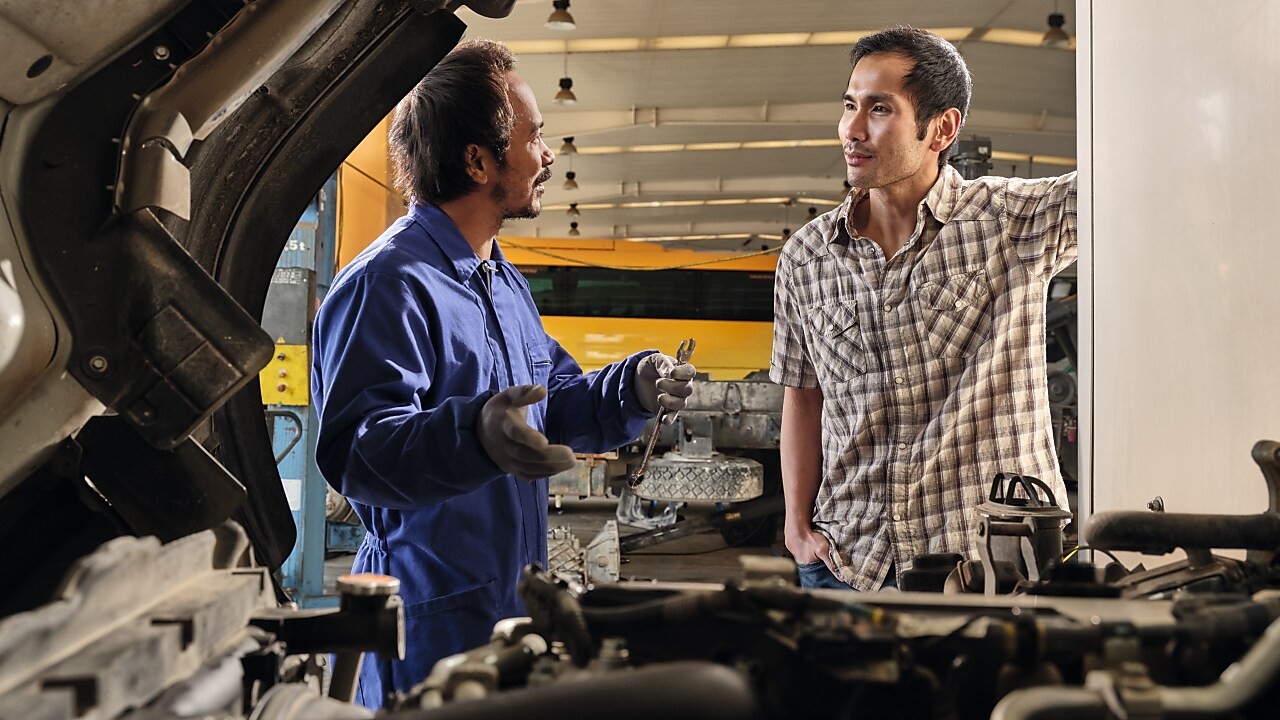 Mechanic talking to a customer over an engine
