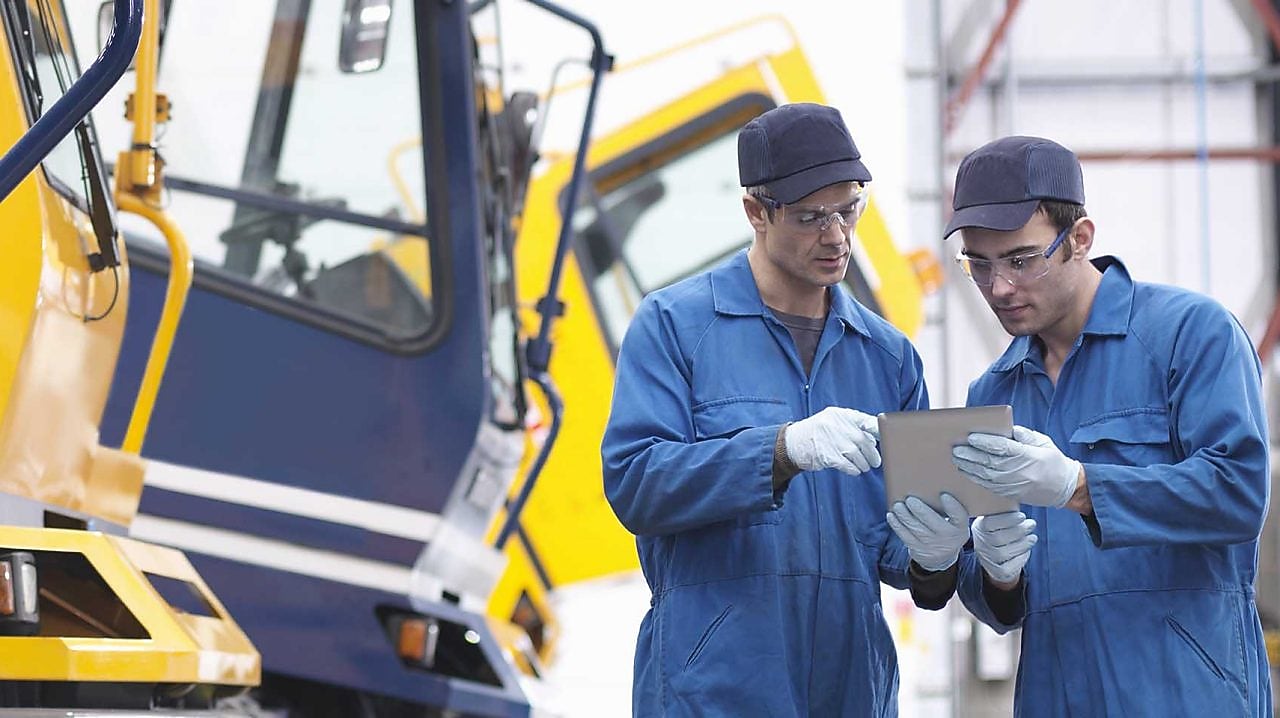Engineers check details on digital tablet in truck repair factory