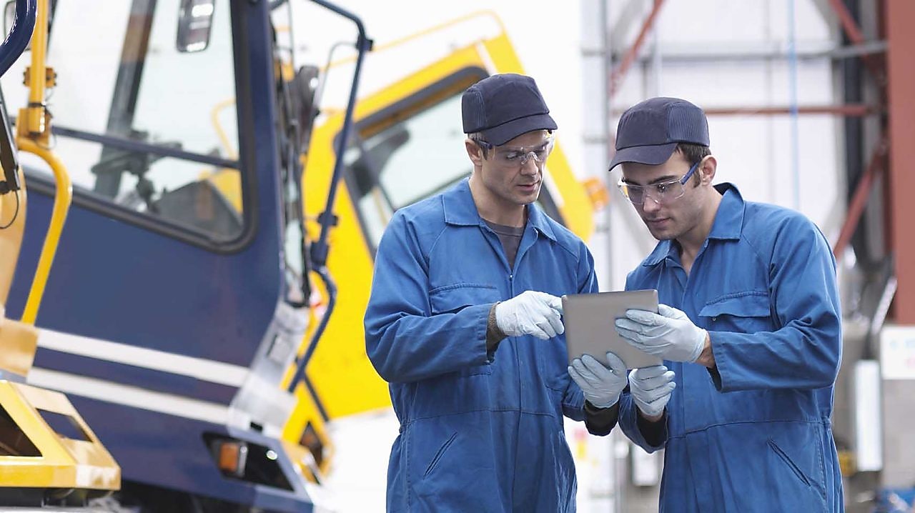 Engineers check details on digital tablet in truck repair factory
