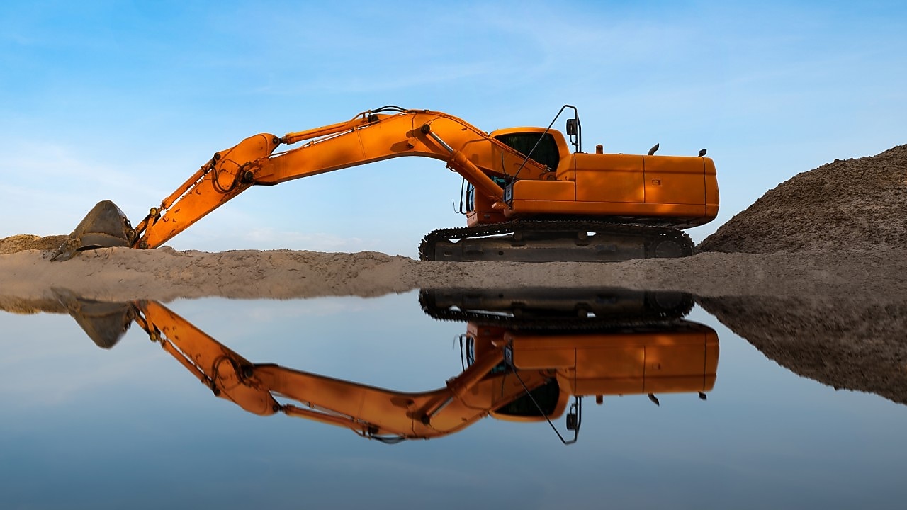 Excavator on site at the seaport sprinkles sand soil