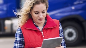 Worker looking at a tablet device in front of trucks