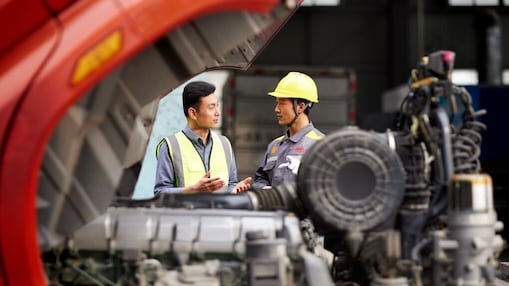 Workers talking in front of a truck engine