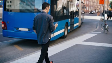 man-walking-on-sidewalk-while-using-mobile-in-city