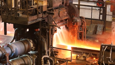 Worker mixing liquid metal in a furnace