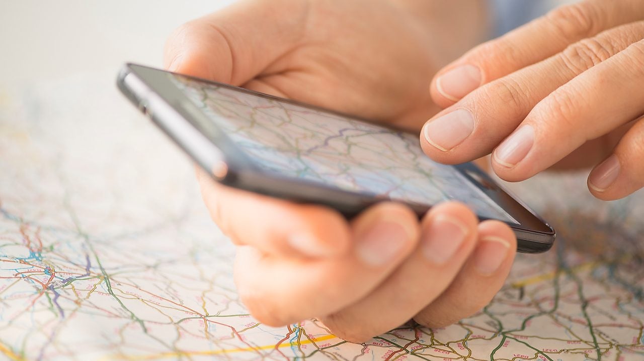 Close-up of hand using smartphone over map