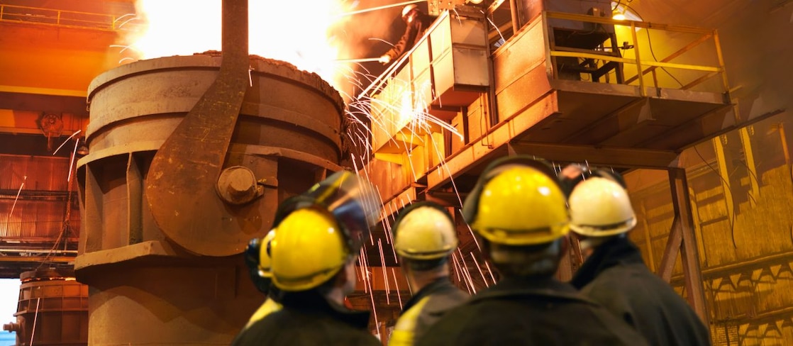 Workers in hard hats inspecting a furnace