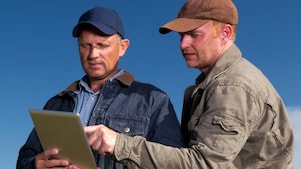 Two farmers reviewing information on tablet