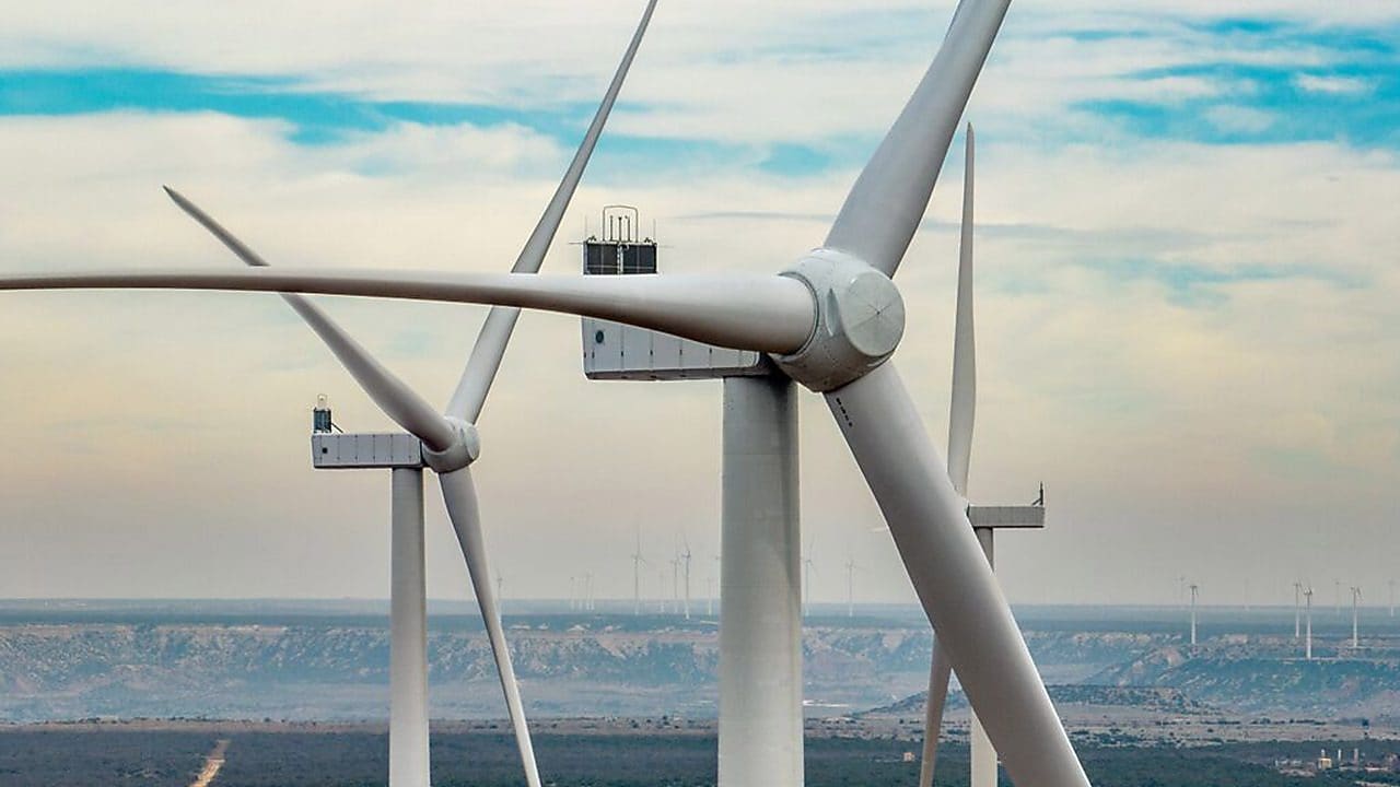 Close-up view of large wind turbines in an open landscape, showcasing wind energy infrastructure.