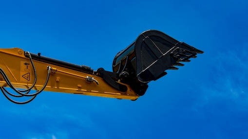 A yellow digger pointing up into a blue sky