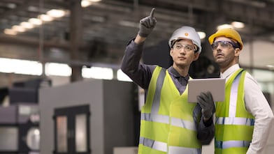 Two engineers looking at tablet in hard hats