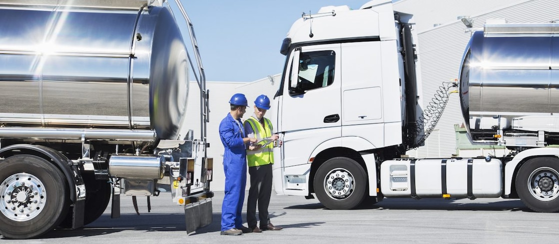 Workers talking next to two tanker lorries