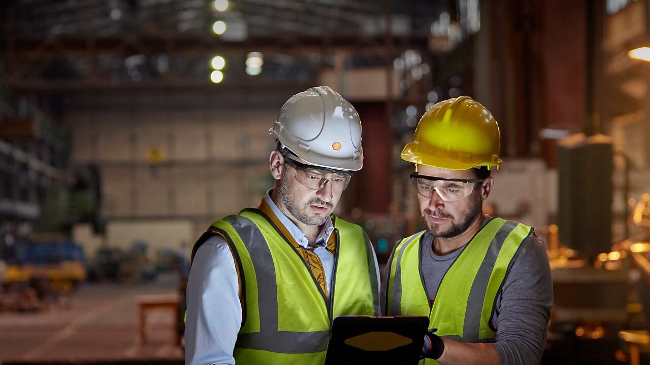 Male engineer and worker using digital tablet in dark factory