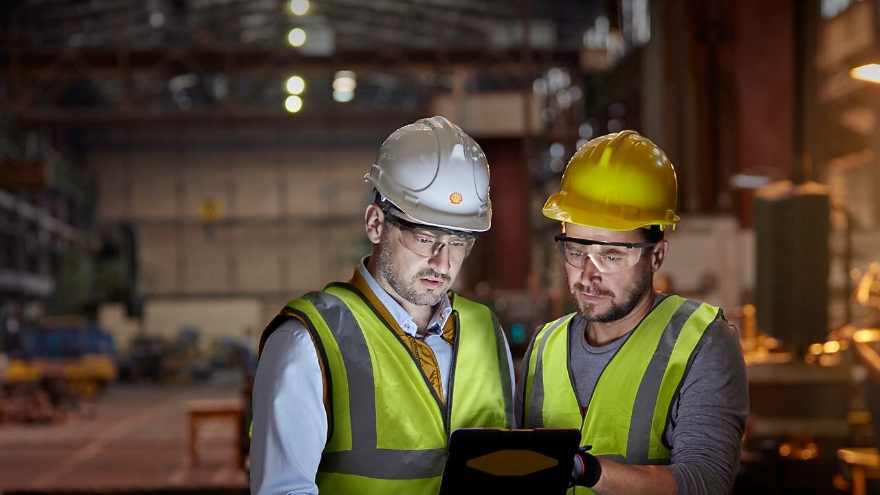 Male engineer and worker using digital tablet in dark factory