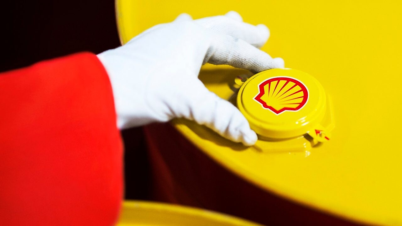 A Shell expert adjusts the lid of a barrel of lubricant displaying the Shell logo