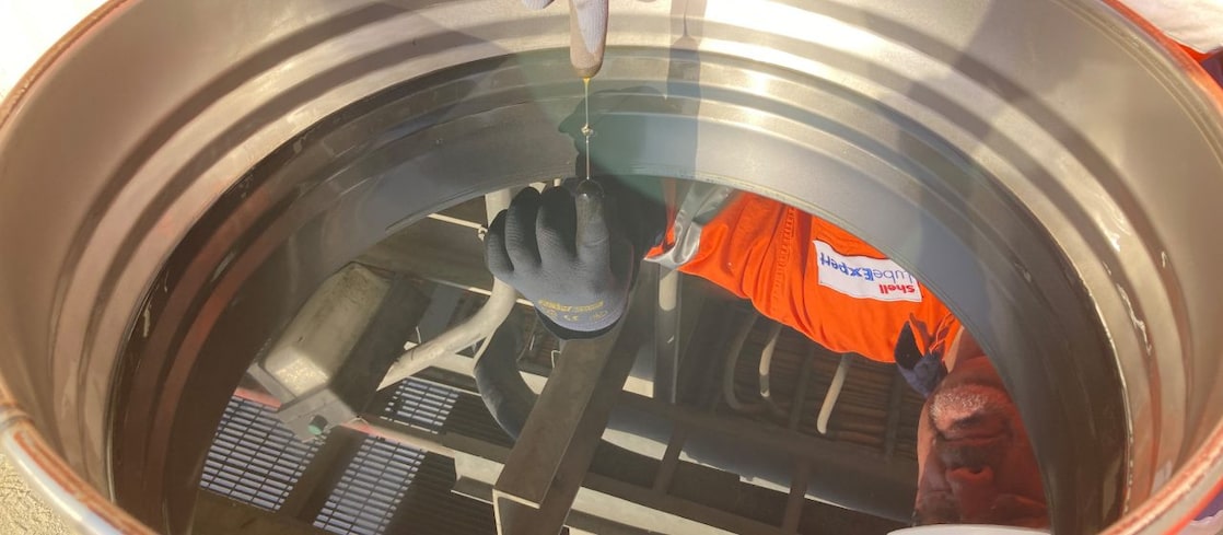 Man looking into lubricant barrel