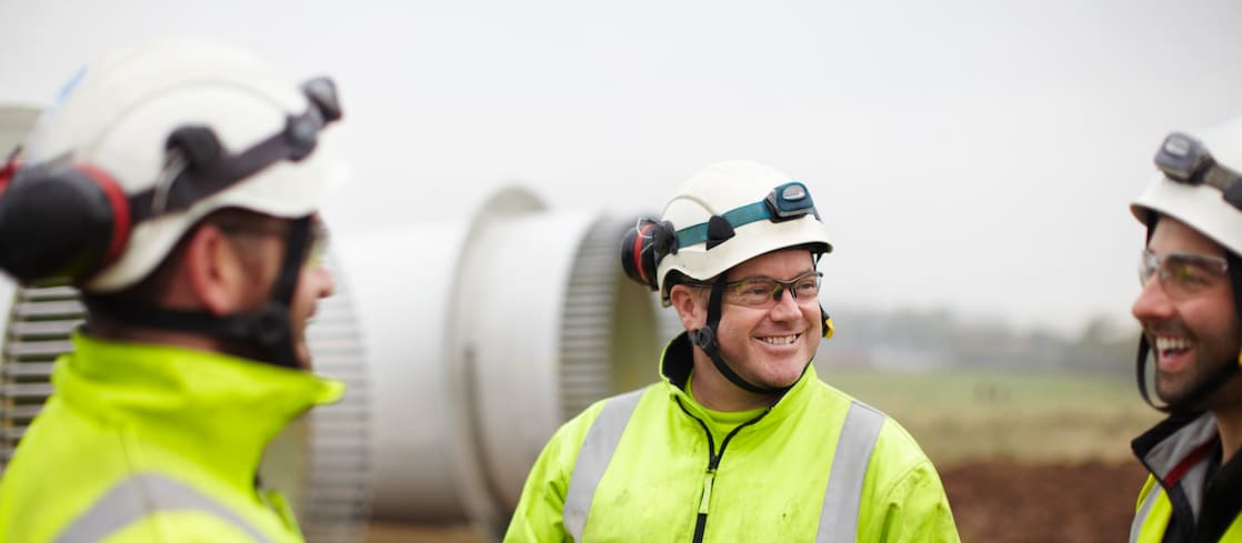 Three engineers wearing high-vis jackets with white hard hats and safety glasses.