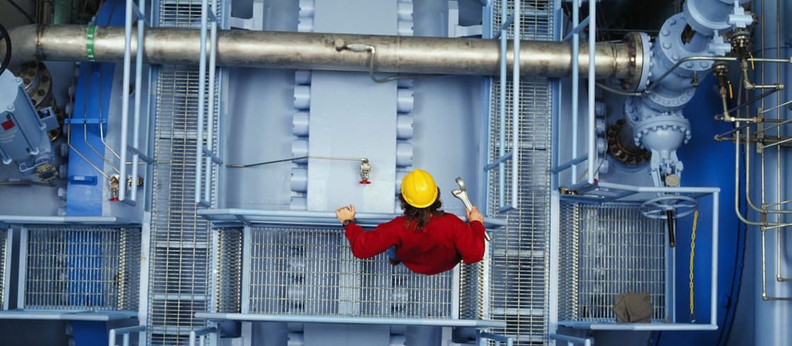 Worker inspecting valve at power station