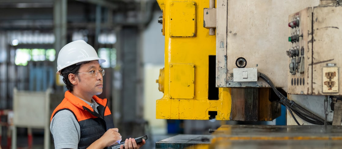 Engineer wearing a white hard hat inspecting machinery