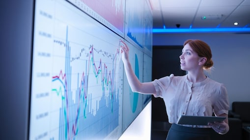Businesswoman studying graphs on screens