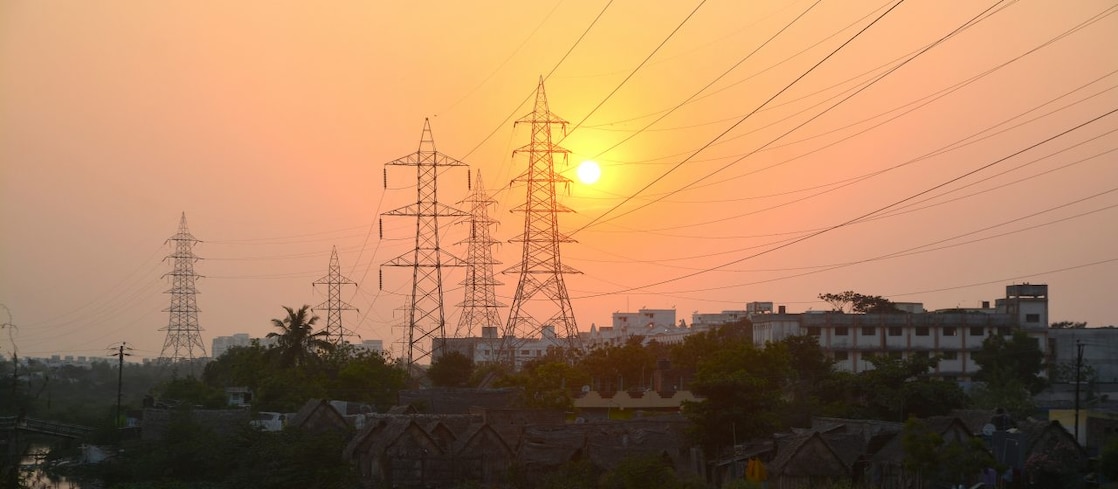 Sun setting over hills with pylons and transformers in the distance