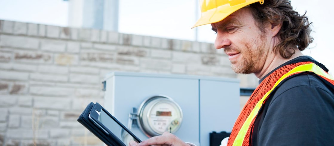 Engineer wearing a yellow hard hat looking at tablet