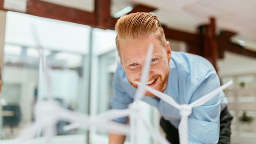 Businessman in office looking at models of wind turbines