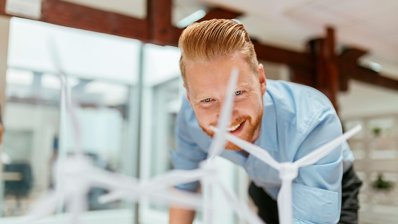 Businessman in office looking at models of wind turbines