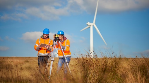 Engineers using a builder's level to plan out the expansion of the wind farm site.