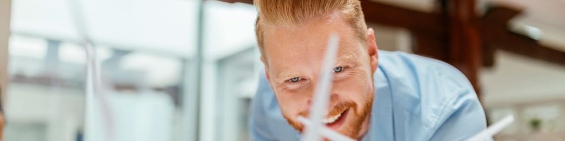 Businessman in office looking at models of wind turbines