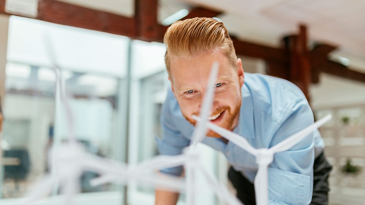 Businessman in office looking at models of wind turbines