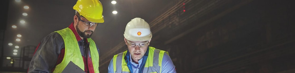 Steelworkers using laptop in dark steel mill