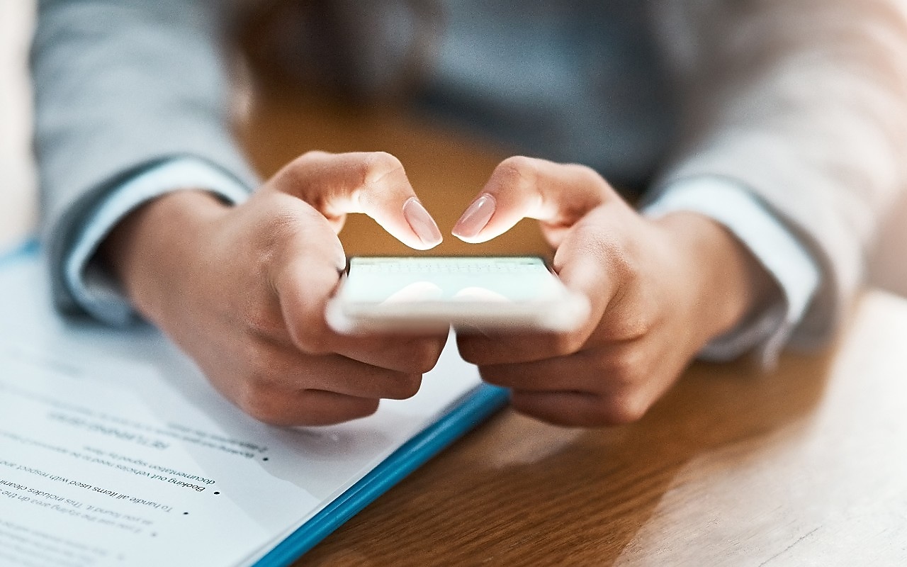 Two hands shown using a mobile device to send an email