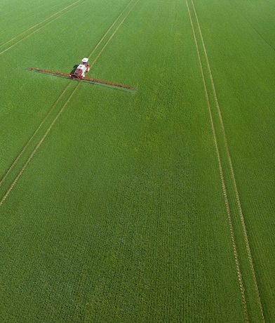 Aerial view of farm with a working combine harvester