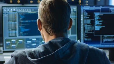 A man looking at a bank of computer screens