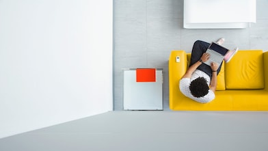 Man sitting on a yellow sofa using a laptop