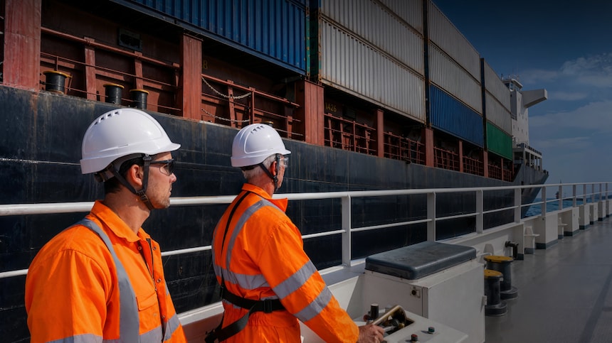 Two engineers walking next to container ship