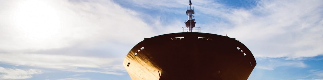 Bow view of cargo ship sailing out of port.