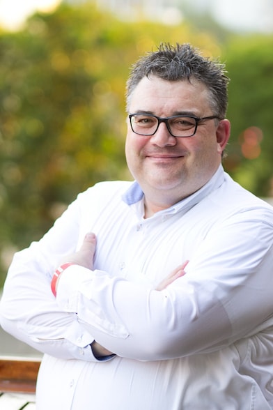 a man standing with folded hands and smiling