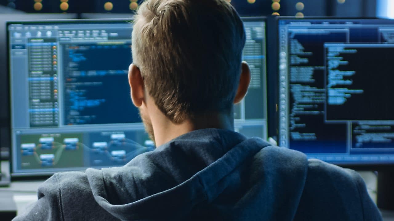 A man looking at a bank of computer screens