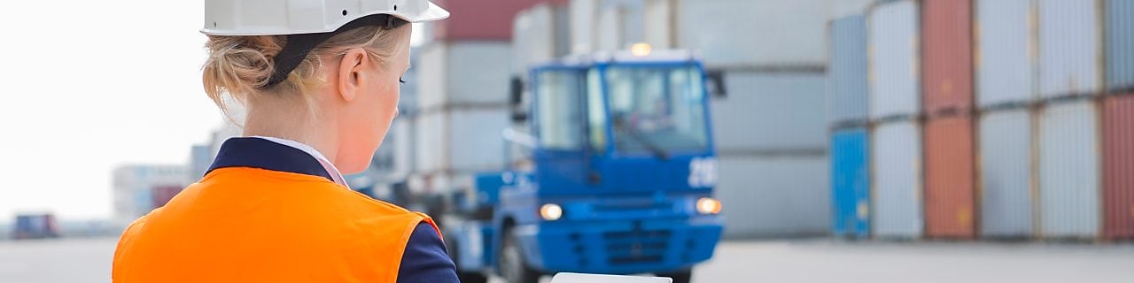 Rear view of female engineer using tablet PC in shipping yard