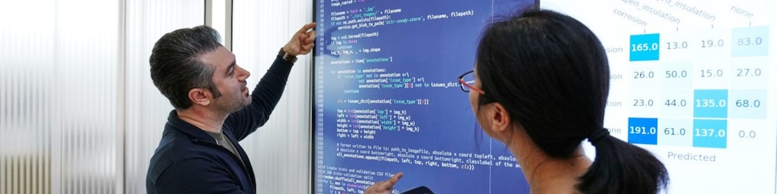 Two team members reviewing code together on a large screen.