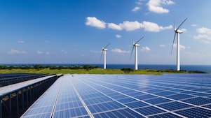 Solar panels with wind turbines in the background