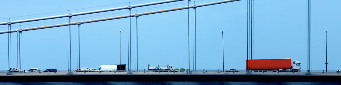 Truck driving along a bridge with blue sky