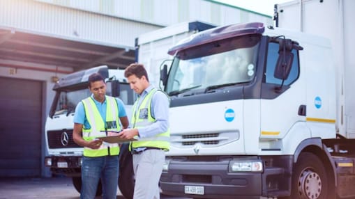 Two men speaking in front of parked trucks