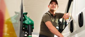 man filling white van up at pump