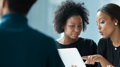 Two women consulting on tablet