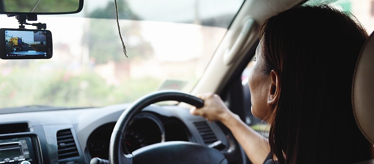 Woman driving and looking at the front mirror