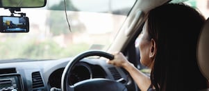Woman driving and looking at the front mirror