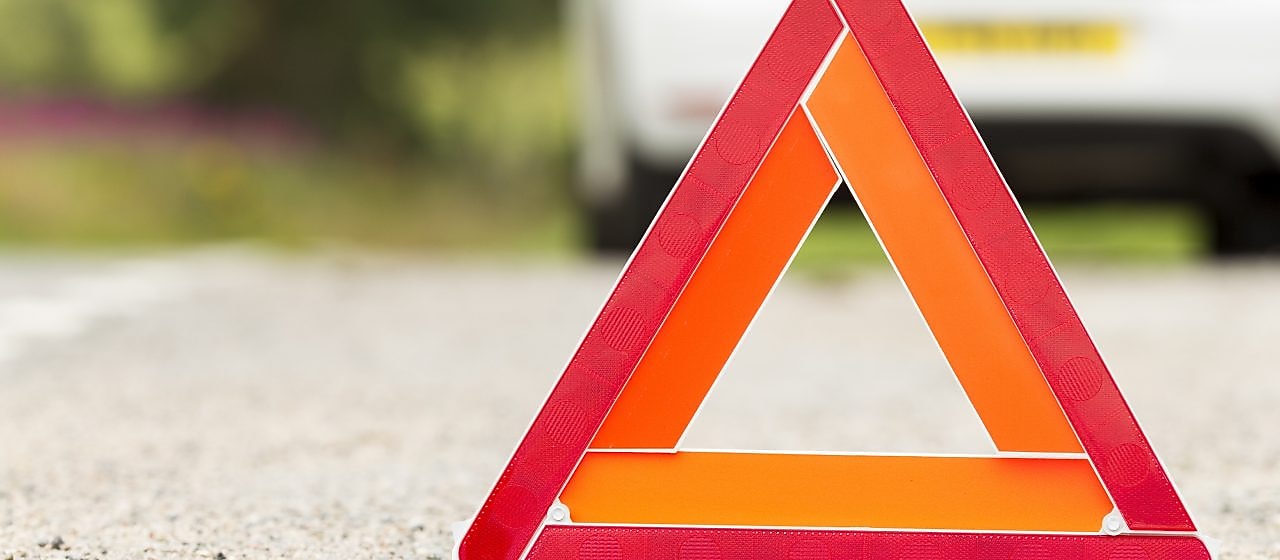 Problems car and a red triangle warning sign on the road