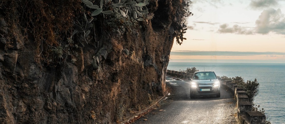 Car driving on a cliff road with the sea on the right